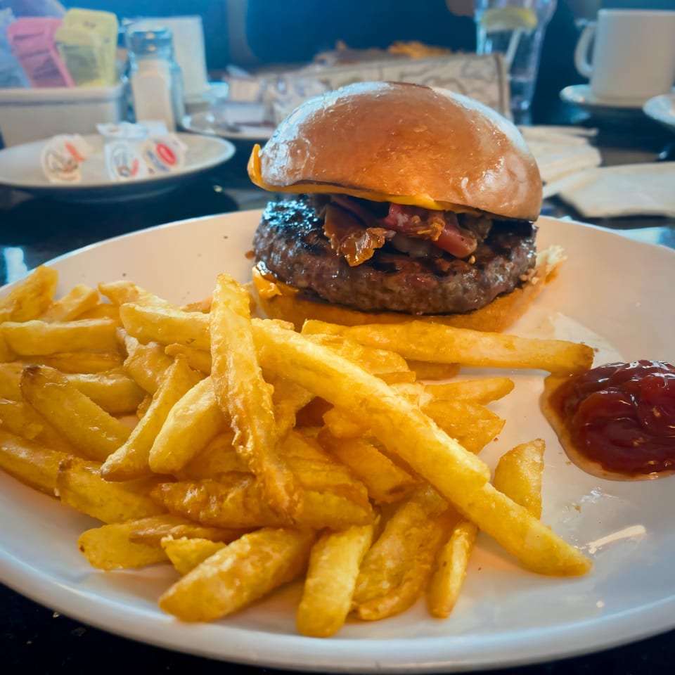 A Parkview Diner cheeseburger with caramelized onions and a side of golden french fries and ketchup.