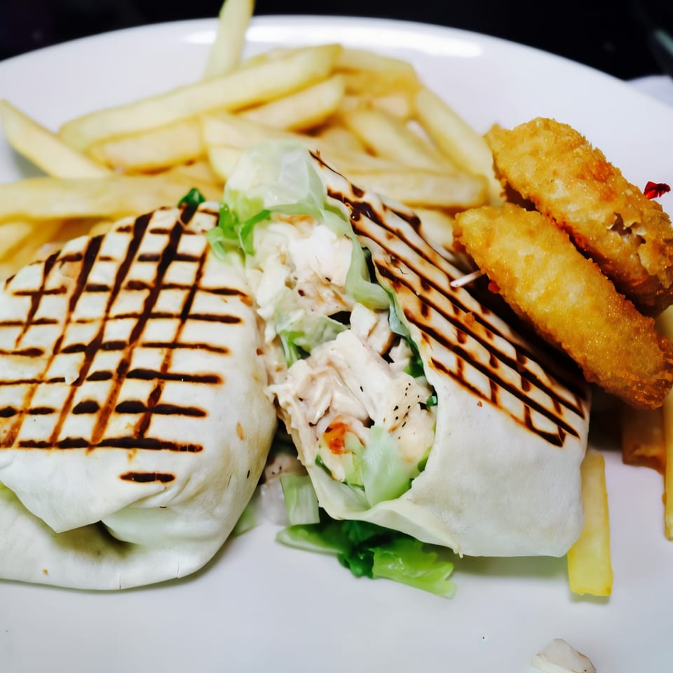 Grilled chicken wrap with lettuce, fries, and two fried mozzarella sticks on a white plate.