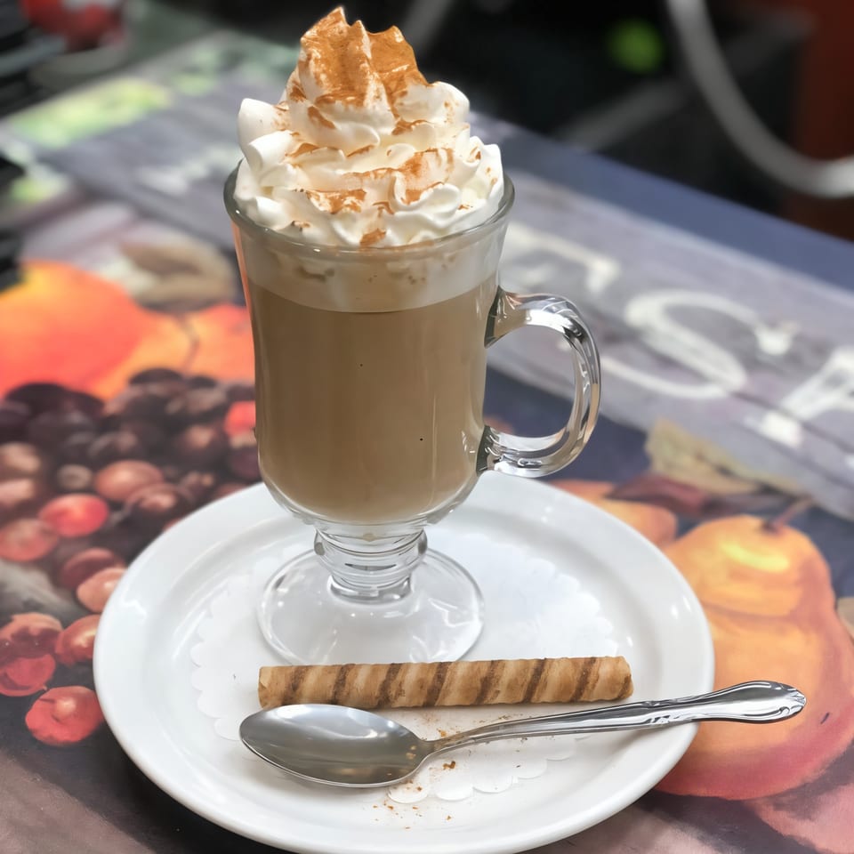 A Parkview Diner latte with whipped cream and cinnamon, served with a wafer cookie and spoon.
