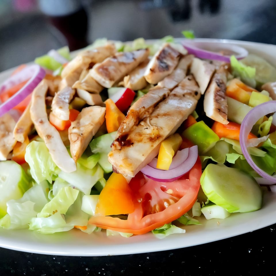 Grilled chicken salad with lettuce, tomatoes, cucumbers, bell peppers, and red onions at Parkview Diner.